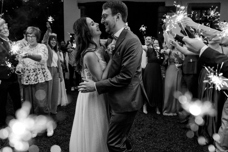 Brautpaar-Gästefoto während des Sparkling Exits: Das Brautpaar tanz inmitten der Gäste, die mit Wunderkerzen um es verteilt stehen